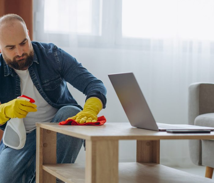 Man cleaning up at home wearing rubber gloves and using spray